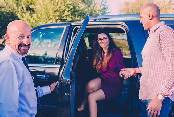 Chauffeur holding door for wine tasting couple