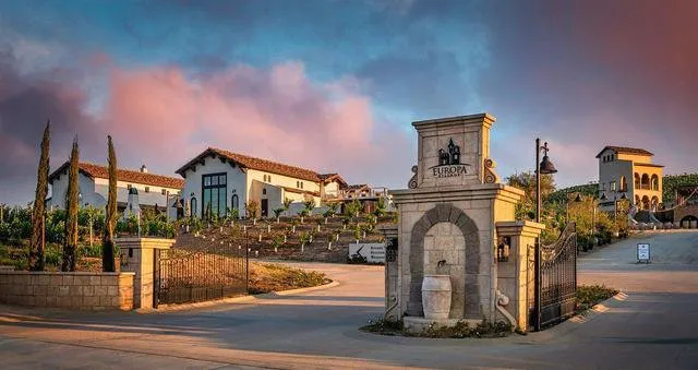 Europa Village in the Background A Glass of Wine Held By a Female Hand in the Foreground
