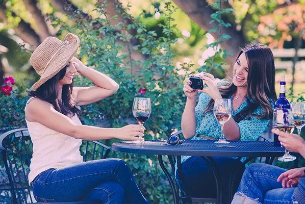 Taking a photo of wine tasting friend in a hat