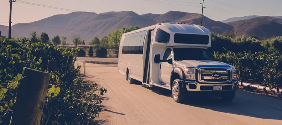 White shuttle on gravel drive between vineyards